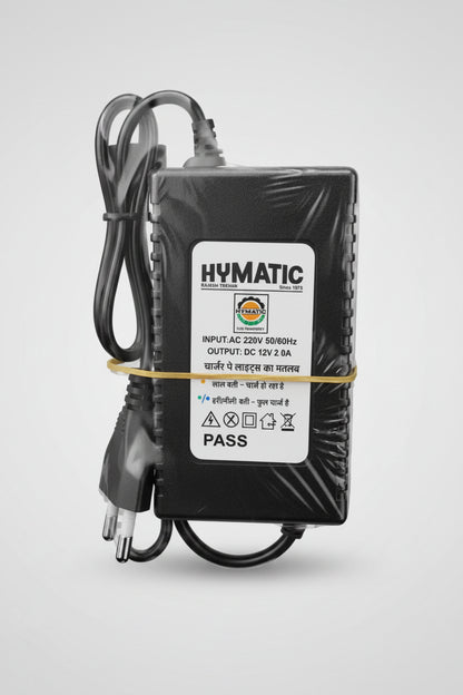 Hymatic mains power adapter with cord, label reads input 220V AC, output DC 12V 2A, bundled with a rubber band.